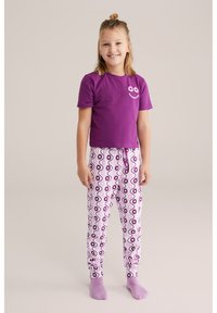 Camisa corta de manga púrpura con un gráfico de flores, combinada con pantalones de pijama blancos con un patrón de flores púrpuras y rosas.