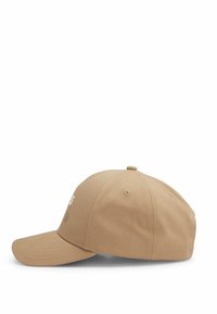 Cappellino da baseball beige con logo ricamato in bianco. Presenta una visiera curva, una parte frontale strutturata e fori di ventilazione sulla parte superiore.