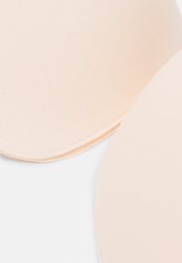 Beige fabric bra cups with a smooth texture. Rounded shape with a slight sheen, featuring a seam along the edge for structural support.