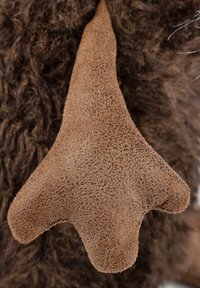 Brown faux fur with a textured, brown, triangular ear. The ear has a soft, suede-like surface and distinct rounded tips.