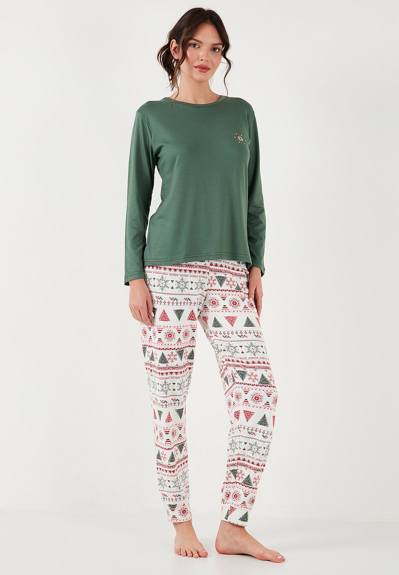 Tricou verde cu mânecă lungă, asortat cu pantaloni albi, care prezintă un model festiv în roșu și verde cu copaci, fulgi de zăpadă și motive de sărbătoare.