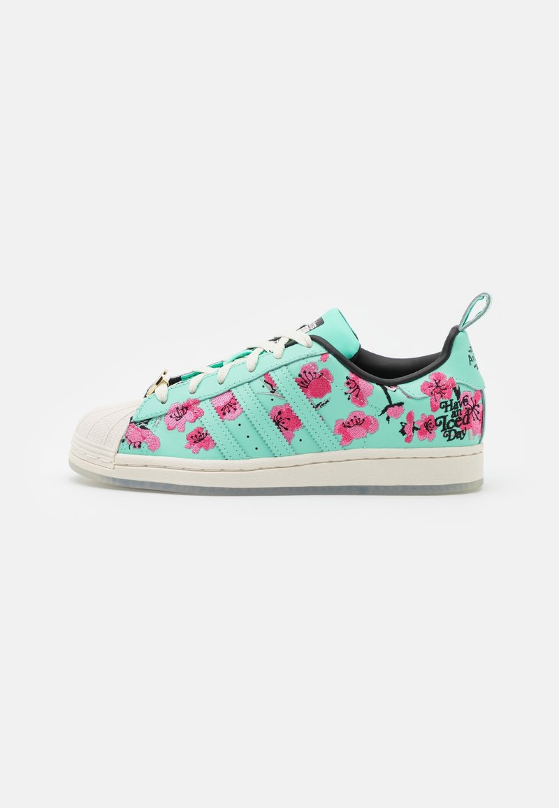 Mint green sneaker with white rubber toe, pink floral embroidery, black inner lining, and "Have an Ice Day" text on heel.