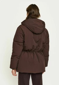 Bruine geïsoleerde jas met capuchon, verstelbare taille en lange mouwen. Soepele textuur en puffy ontwerp voor warmte en comfort.