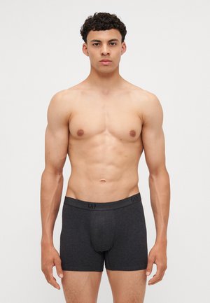 Sötét szürke, puha anyagból készült boxer alsónadrág, logózott elasztikus derékpánttal és szoros illeszkedéssel, bemutatva egy férfi modell által.