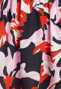 Kangas bermotif yang menampilkan bentuk abstrak dalam warna merah, pink, putih, dan hitam. Tekstur yang ringan dan berkerut dengan desain yang cerah.