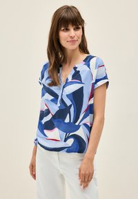 Blusa a maniche corte in tessuto leggero con un motivo astratto di foglie blu e bianche con accenni di rosso; scollatura a V con dettaglio dei bottoni.
