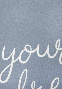 Light blue knit fabric featuring white cursive text. The texture is ribbed, with a subtle pattern from the knitted weave.