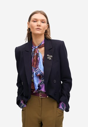Blazer de rayas marinas, blusa floral púrpura con acentos azules, bufanda azul clara, pendientes de aro dorados y pantalones marrones con cinturón.