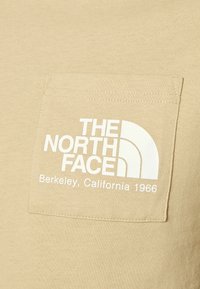 Béžová látková kapsa s bílým logem "THE NORTH FACE" a textem "Berkeley, California 1966" potištěným vpředu.