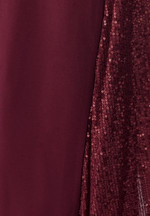 Burgunderrotes Kleid mit glattem Stoff auf der einen Seite und funkelnder Paillettenstruktur auf der anderen Seite, die einen kontrastreichen visuellen Effekt erzeugt.