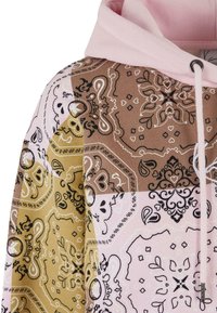 Hettegenser med et lappeteppe-design i rosa, brun og gull med intrikate paisley- og blomster mønstre, laget av myk stoff.