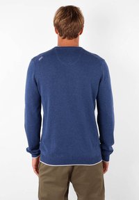 Pull en tricot bleu à manches longues, col arrondi et bord-côte aux poignets et à l'ourlet. Détail de logo subtil sur l'épaule.