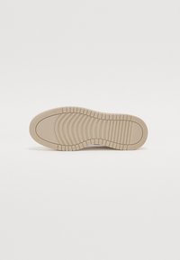 Beige gummisåle med rillet tekstur for grep, med avrundet tå og glatte kanter. Flat design uten synlige logoer.
