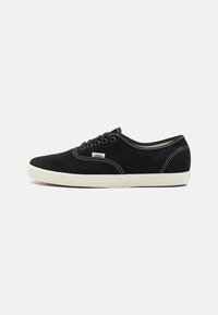 Zwarte suede sneakers met witte rubberen zolen, ronde neus, zesgaatjes vetersluiting en witte stiksels op de naden.