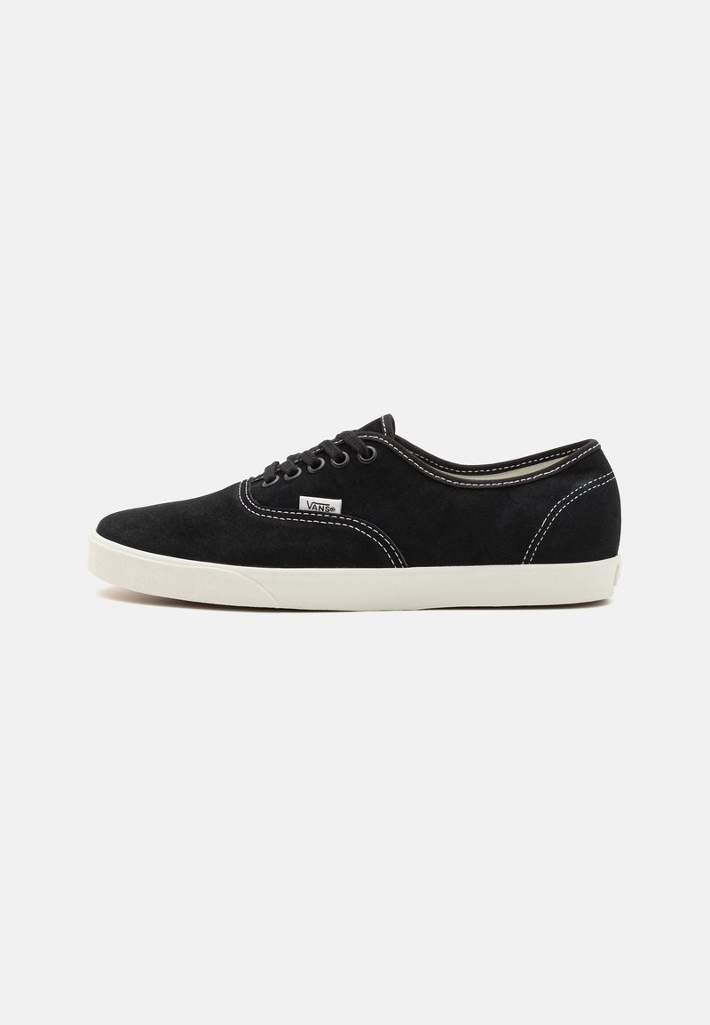 Zwarte suede sneakers met witte rubberen zolen, ronde neus, zesgaatjes vetersluiting en witte stiksels op de naden.