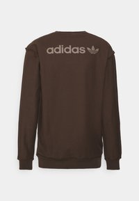 Brun sweatshirt med långa ärmar, rundad nacke och slitna detaljer. Har en stor grå "adidas"-logotyp och trefoil-ackent på baksidan.