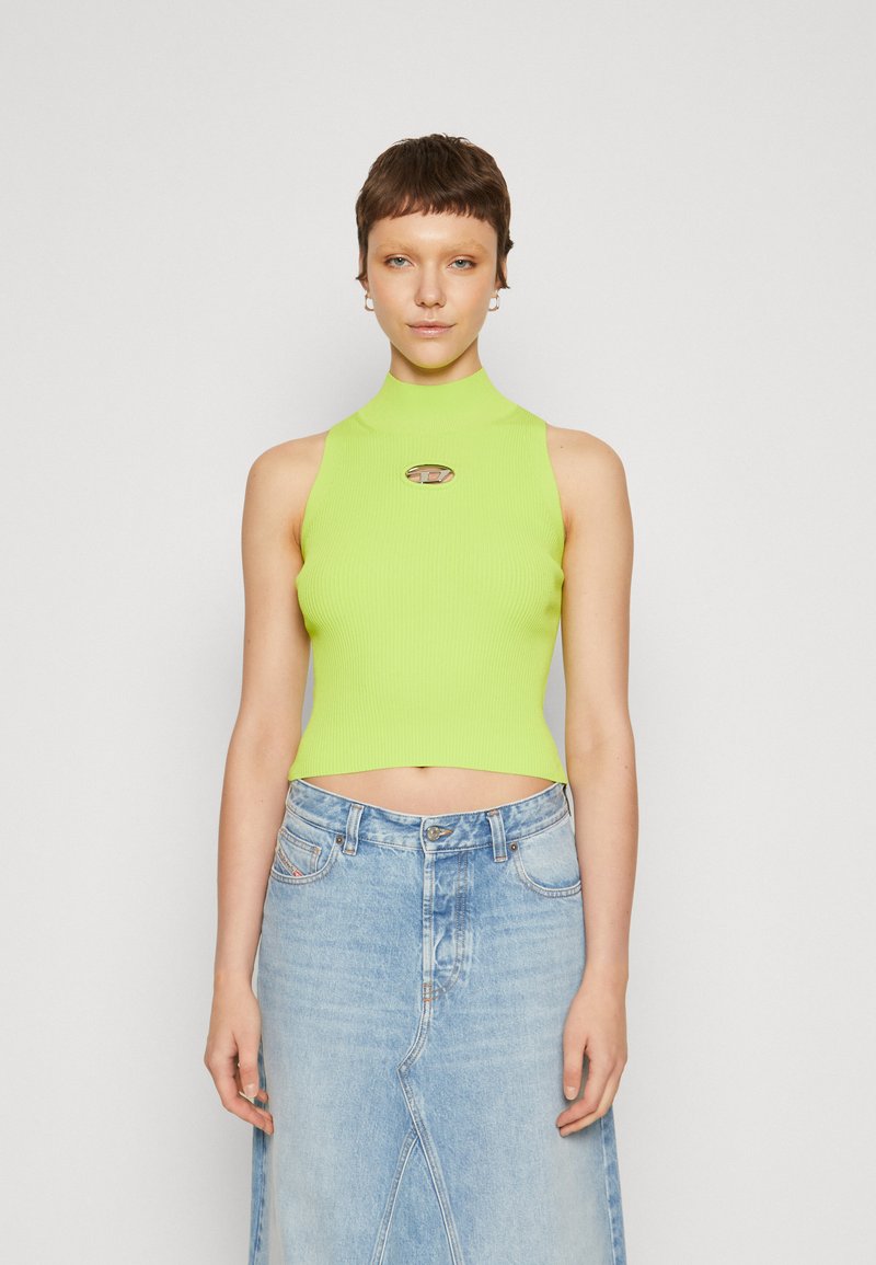 Lime green, ribbed crop top with a high neck and logo accent at the center, paired with a light blue denim skirt featuring a front slit.