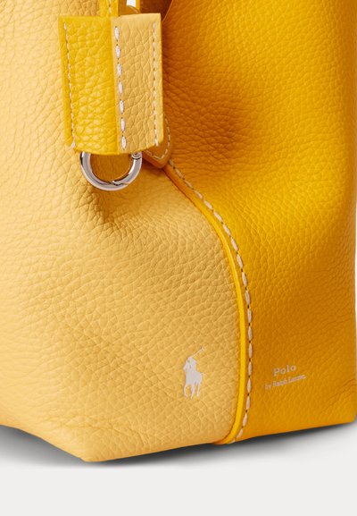 Gult tekstureret lædertaskehjørne med hvide syninger, sølvmetalring og Polo by Ralph Lauren-logo i hvid.
