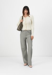 Cardigan a coste di colore beige chiaro con scollo rotondo e chiusura a bottoni; pantaloni grigi a vita alta; ballerine rosa chiaro; borsa a tracolla verde oliva.