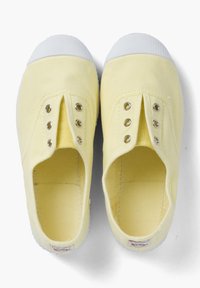 Żółte płócienne trampki wsuwane z białymi gumowymi podeszwami, posiadające metalowe oczka i teksturowane wnętrze. Prosty design, bez sznurowadeł.
