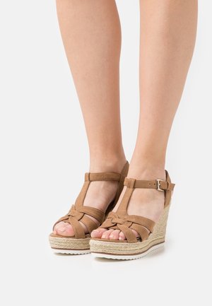 Sandales compensées en daim marron avec une semelle espadrille tressée, bout ouvert et bride de cheville avec une boucle en métal.