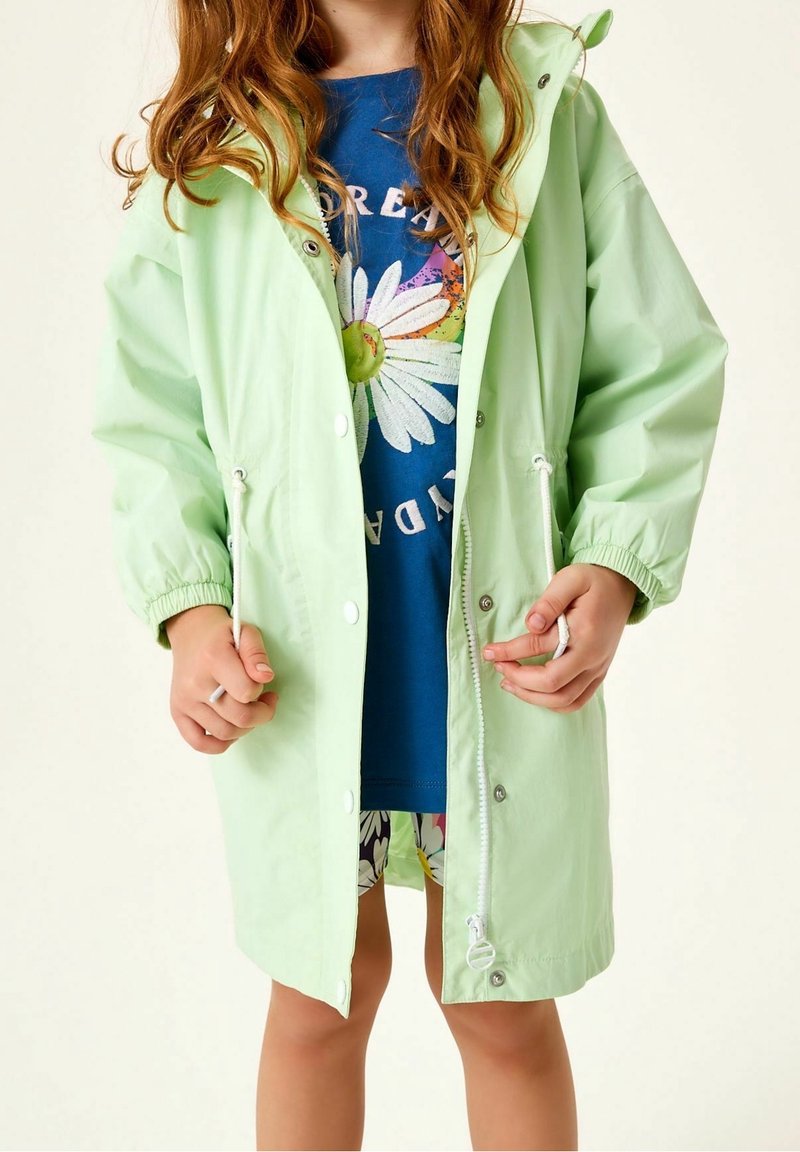 Hellgrüne wasserdichte Jacke mit Kapuze, elastischen Bündchen und Kordelzug in der Taille. Verfügt über Druckknöpfe und eine weiche, glatte Textur.