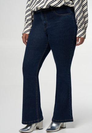 Donkerblauwe wijde jeans van denim, met contrasterende stiksels en een middellange taille. Gepaard met metallic hakken.