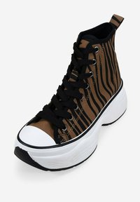Zapatillas altas con una parte superior de lienzo a rayas marrón y negro, cordones negros y una suela de goma blanca con un diseño texturizado.