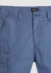 Pantalon décontracté bleu Levi's avec fermeture à boutons sur le devant, passants de ceinture, poches latérales inclinées et une poche cargo sur la jambe gauche.