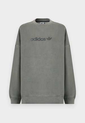 Pelēks džemperis no maigas auduma, ar ribām apvērtām aprocēm, apaļu apkakli un tumšākas krāsas Adidas logotipu, kas izdrukāts priekšpusē.