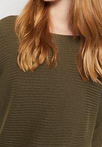 Olive green ribbed sweater with a square neckline and soft texture, featuring a relaxed fit and flowing sleeves.