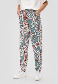 Spodnie w turkusowym kolorze z wzorem paisley, zawierające odcienie czerwieni i bieli. Elastyczny pas i boczne kieszenie. Luźny krój.