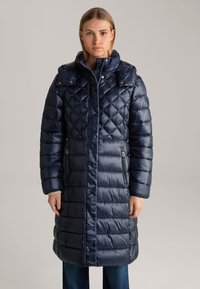 Marineblauwe gewatteerde pufferjas met lange mouwen, hoge kraag, ritszakken en een glanzende textuur. Bevat decoratieve hardware en heeft een lengte tot de knieën.