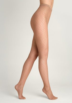 Nogi u przezroczystych, cielistych rajstopach w wzór diamentów, stojące na palcach na jednolitym tle.