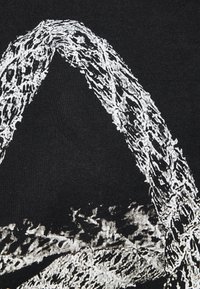 Svart tyg med ett vitt abstrakt mönster som liknar överlappande linjer och former, vilket skapar en texturerad visuell effekt.