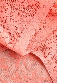 Țesătură de dantelă coral cu modele florale. Suprafață texturată, secțiuni transparente și decupaje intricate creează un efect stratificat. Moale și ușoară.