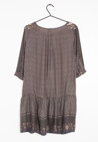 Grå mönstrad klänning med trekvartslånga ärmar, insvängd midja och volangslut. Har dekorativa detaljer på axlarna i jordnära toner.