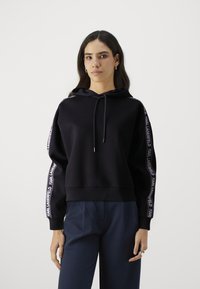 Zwarte hoodie met een trekkoord, voorzien van witte "KARL LAGERFELD" branding langs de mouwen. Zacht materiaal, comfortabele pasvorm, geribbelde manchetten.