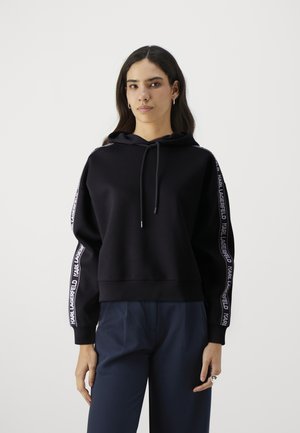 Black hoodie with a drawstring, featuring white "KARL LAGERFELD" branding along the sleeves. Soft fabric, relaxed fit, ribbed cuffs.