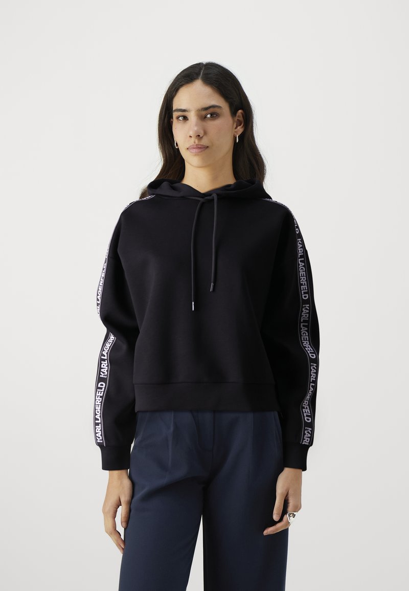 Zwarte hoodie met een trekkoord, voorzien van witte "KARL LAGERFELD" branding langs de mouwen. Zacht materiaal, comfortabele pasvorm, geribbelde manchetten.