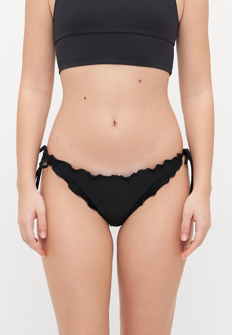 Crni bikini donji dio s naboranim rubom, podesivim bočnim vezicama i glatkom teksturom. Tkanina je meka i u solidnoj boji.