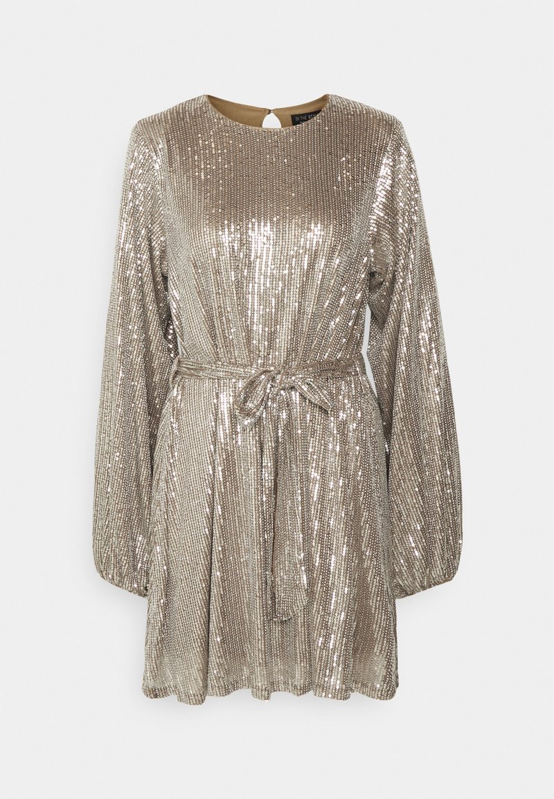 Robe mini à manches longues, en sequins argentés métalliques, avec un col rond, une ceinture cintrée à la taille et une jupe légèrement évasée sur un fond uni.