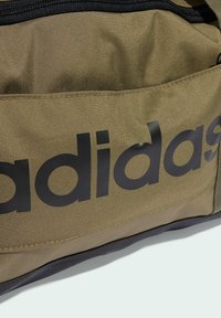 Olivengrøn sportstaske med sorte accenter, prydet med et stort sort "adidas" logo, lavet af slidstærkt stof med en struktureret overflade.