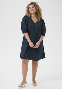 Vestido de manga corta azul marino con escote en V, que presenta mangas abullonadas y un corte relajado. Textura suave con una tela ligera.