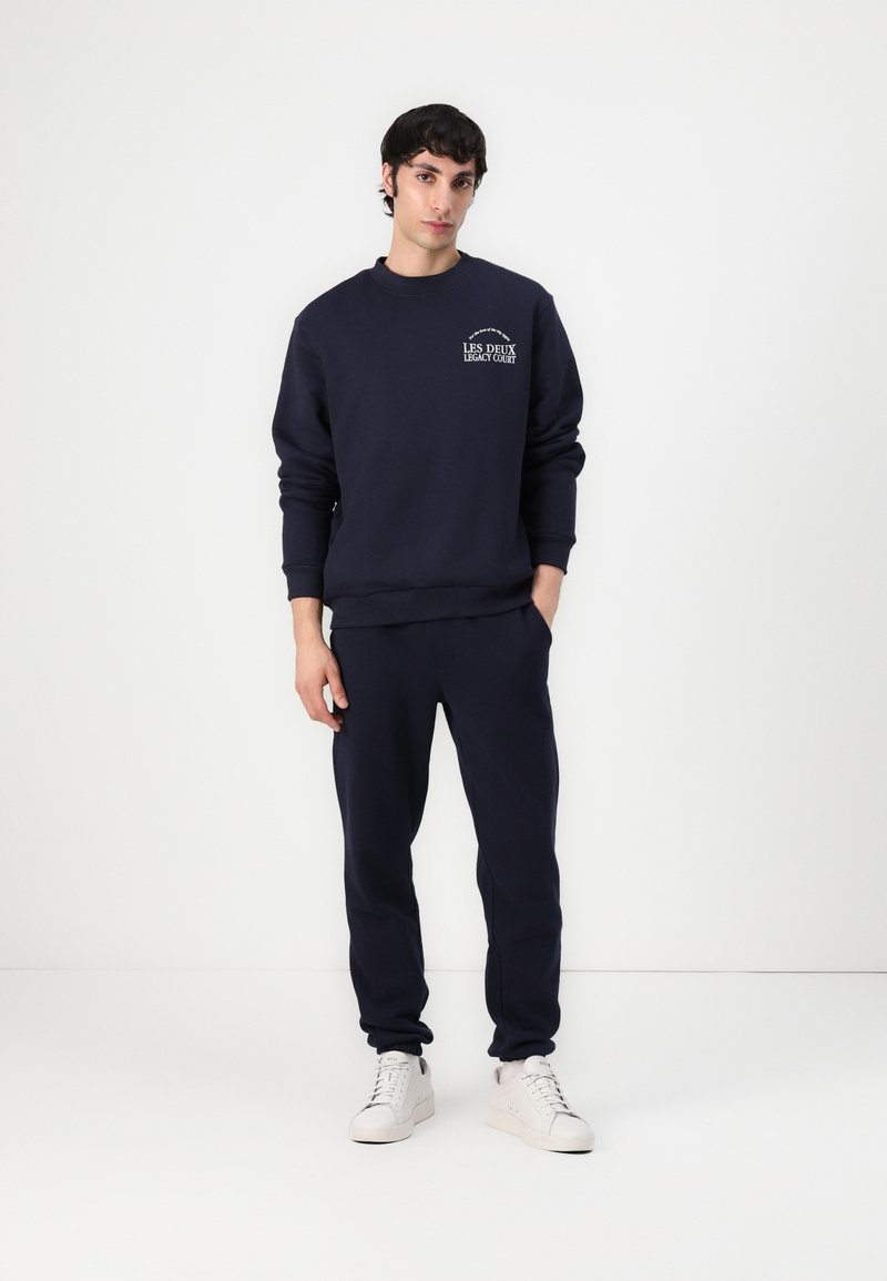 Marineblå sweatshirt og matchende joggers i blødt stof. Sweatshirten har et lille logo på brystet. Casual, afslappet pasform med ribbede manchetter.