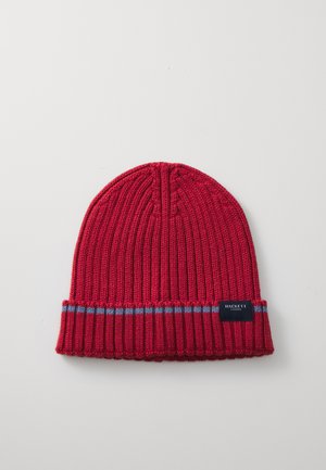Red knitted beanie with a ribbed texture and fold-over cuff. Features a blue stripe above the cuff and a small black label with "HACKETT LONDON."