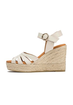 Sandales compensées blanches à brides avec une plateforme en jute tressé, une sangle à la cheville avec une boucle en or, et une finition lisse semblable au cuir.