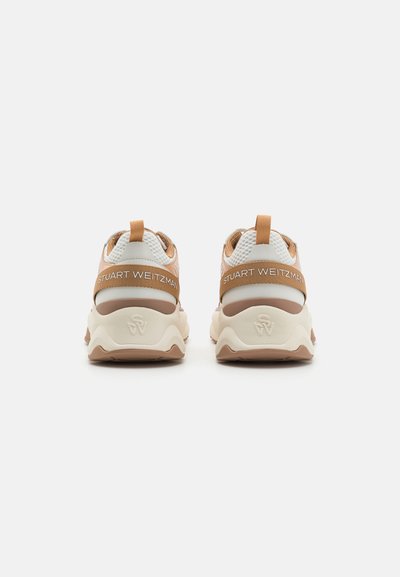 Zapatillas con parte superior de malla en beige y marrón, que cuentan con una suela gruesa y texturizada, lengüetas y el logo 'STUART WEITZMAN' en la parte posterior.