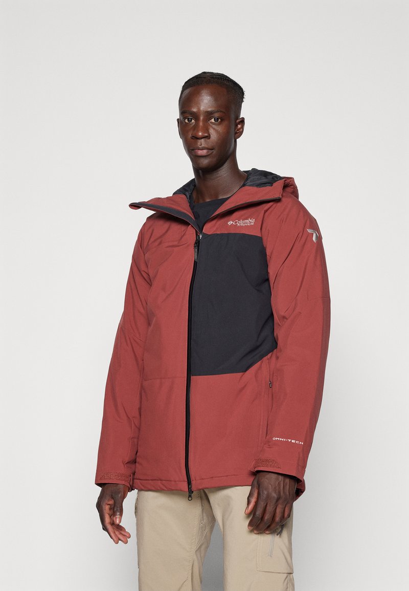 Giacca con cappuccio rossa e nera, con chiusura a zip, polsini elasticizzati e molteplici tasche; realizzata in materiale resistente all'acqua per uso all'aperto.