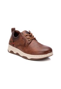 Zapato de cuero marrón con puntera redondeada, cordones en contraste en color marrón claro y un collar acolchado. Presenta una suela gruesa, beige, con detalles texturizados.